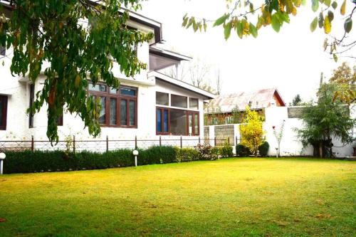 une grande maison blanche avec une pelouse devant elle dans l'établissement Feather Stays - 4 BHK Apartment in a Villa, à Srinagar