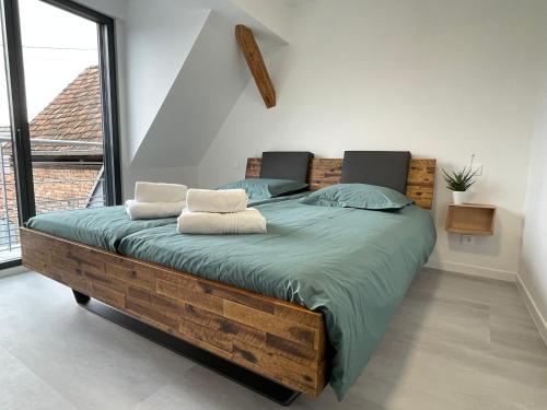 1 dormitorio con cama de madera y ventana grande en Les Duplex Solaires en Duppigheim