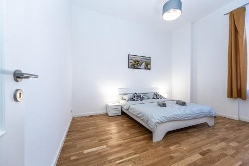 a white bedroom with a bed and a wooden floor at Cozy apartment in the heart of Prague in Prague