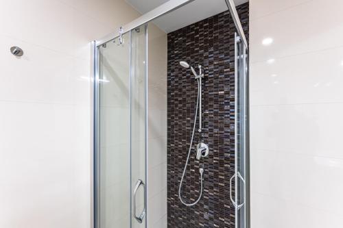 a shower with a glass door and a brick wall at Cozy apartment in the heart of Prague in Prague