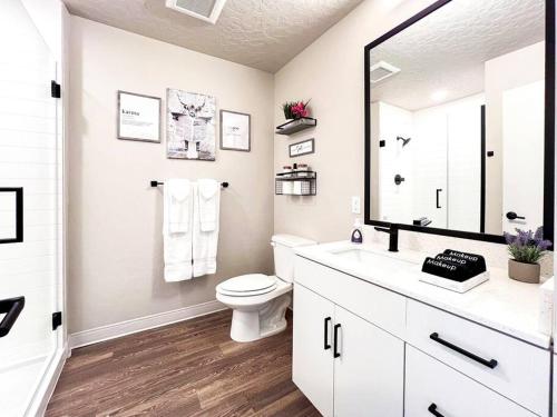 a white bathroom with a toilet and a large mirror at Boho-Luxe Studio - Pink Accents & Mountain Calm in Boise