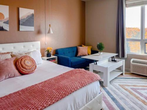 a bedroom with a bed and a blue couch at Boho-Luxe Studio - Pink Accents & Mountain Calm in Boise