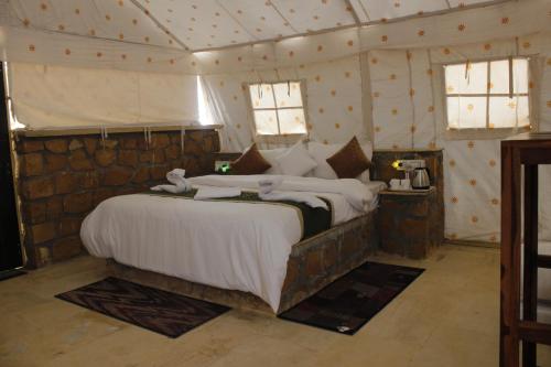 Desert island Camp & Resort Jaisalmer في Sām: غرفة نوم بسرير كبير في خيمة