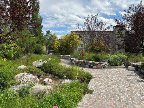 a garden with a brick path and flowers and a building at El Carmelo Mountain Lodge in Potrerillos