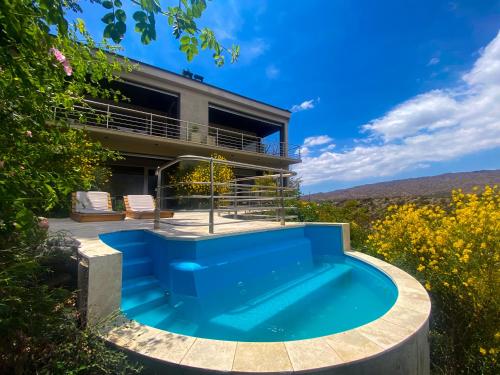 una casa con una piscina azul delante de ella en El Carmelo Mountain Lodge en Potrerillos