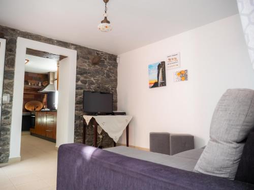 a living room with a couch and a tv at Casa dos Anjos in Ponta do Sol