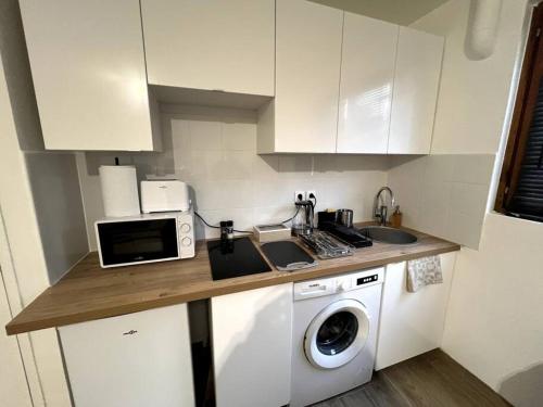 a kitchen with a washing machine and a microwave at Appartement proche tramway in Vitry-sur-Seine