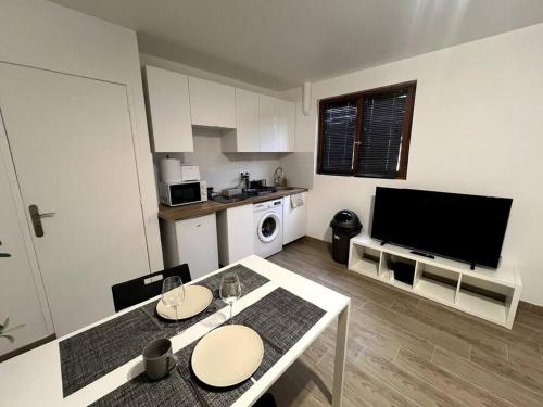 a kitchen with a table and a tv in a room at Appartement proche tramway in Vitry-sur-Seine