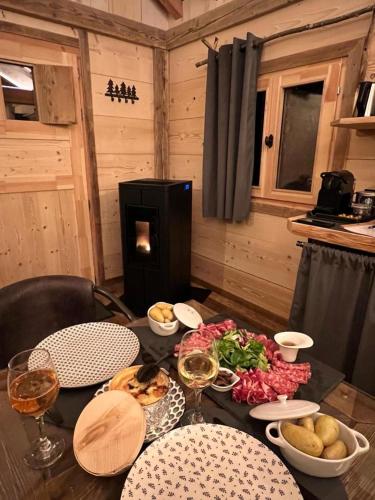 a table with food and glasses of wine in a cabin at Les Écrins du Val de Mouthe, JURA in Petite Chaux