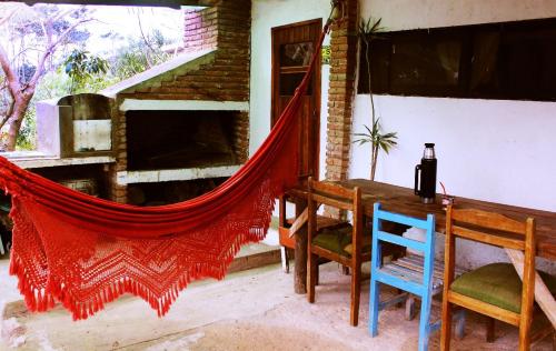 ein Esszimmer mit einem Tisch und einem roten Netz in der Unterkunft Arcadio Hostel Punta del Diablo in Punta Del Diablo