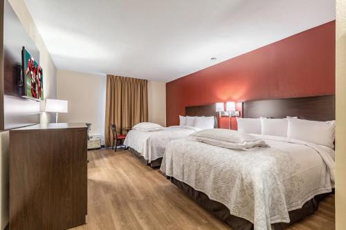 a hotel room with two beds and a red wall at Red Roof Inn PLUS & Suites Houston - IAH Airport SW in Houston