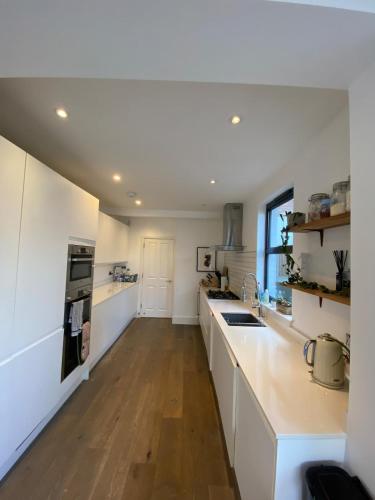 een keuken met witte kasten en een houten vloer bij Stunning 4BD House wLarge Garden - Finsbury Park! in Londen
