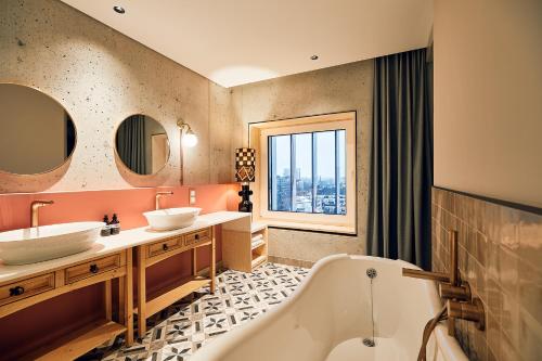 een badkamer met 2 wastafels, een bad en een raam bij Villa Viva Hamburg in Hamburg
