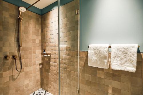 a bathroom with a shower with towels on a glass door at Villa Viva - ein Haus das Brunnen baut in Hamburg