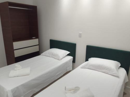 two twin beds in a room with a tv at Apartamento Sol e Mar in Itapema