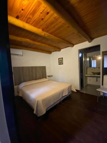 1 dormitorio con cama blanca y techo de madera en Hotel Cristobal de Colón en Colón
