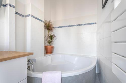 a bathroom with a tub and a potted plant at Calme, soleil, plage - Catalans in Marseille