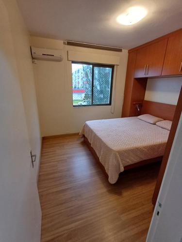 sypialnia z łóżkiem i oknem w obiekcie Ap dos primos w mieście Capão da Canoa