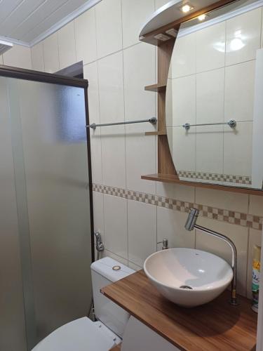 a bathroom with a sink and a toilet and a mirror at Ap dos primos in Capão da Canoa