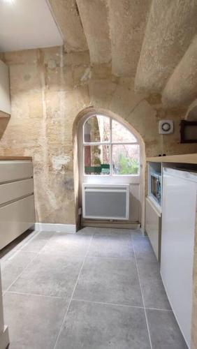 Il comprend une cuisine dotée d'une fenêtre cintrée et d'un grand carrelage. dans l'établissement Studio sur patio au coeur des Chartrons, à Bordeaux