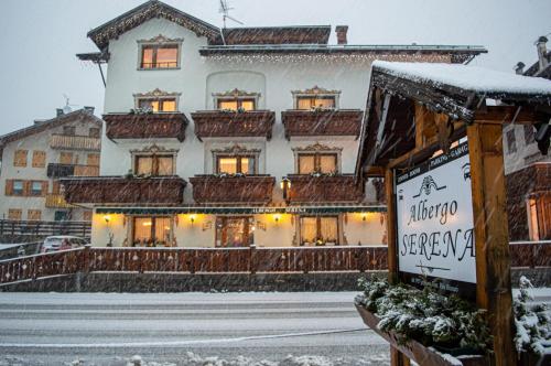a snow covered building with a sign in front of it at Albergo Serena in Auronzo di Cadore