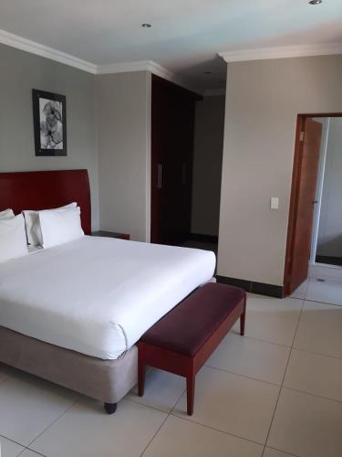 a bedroom with a large white bed and a television at Tamboti Guest Lodge in Pretoria