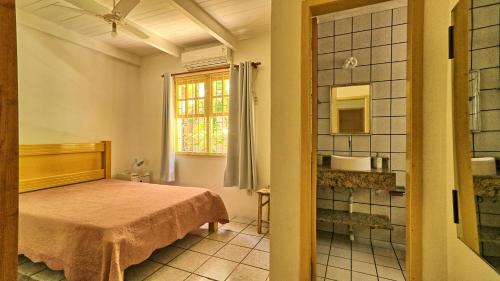 a bedroom with a bed and a window and a mirror at #018 Casa 2 minutos a pé da Praia de Palmas in Governador Celso Ramos