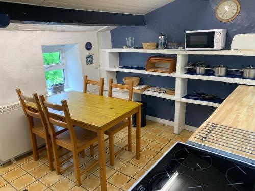 a kitchen with a wooden table and chairs at Garbutt Cottage in Langthwaite