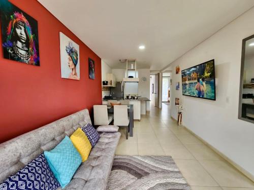 ein Wohnzimmer mit einem Sofa und einer roten Wand in der Unterkunft Apartamento Campestre cerca a Armenia y Parque del Cafe E306 a 5 minutos del Aeropuerto en La Tebaida in Armenia