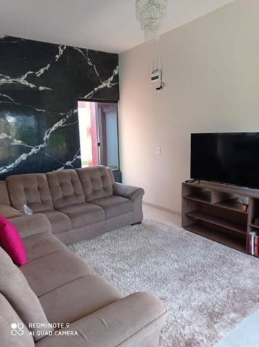 a living room with a couch and a flat screen tv at casa com piscina, 03 quartos, ótima localização! in Bonito