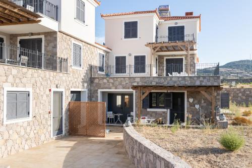 a large white house with a stone wall at Lampetos Houses Molyvos in Mithymna