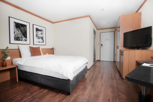 a bedroom with a bed and a flat screen tv at HOTEL ENGEL LIESTAL - Business & Lifestyle in Liestal