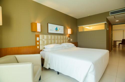 a bedroom with a large white bed and a couch at Hotel Luzeiros São Luis in São Luís