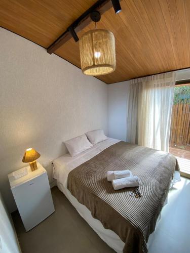 a bedroom with a bed with a lamp and a window at Noronheiro Boutique & House in Fernando de Noronha