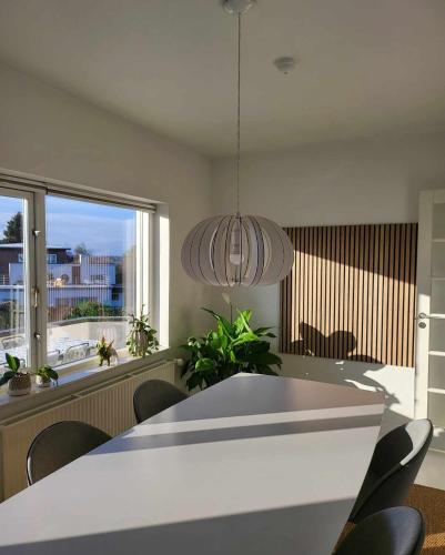 a dining room with a table and chairs and a large window at Moderne villalejlighed på 110 kvm + stor terrasse in Viby