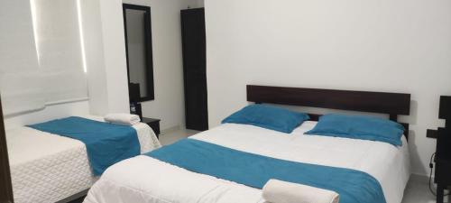 a bedroom with two beds with blue pillows at Hotel Mykonos Manta in Manta
