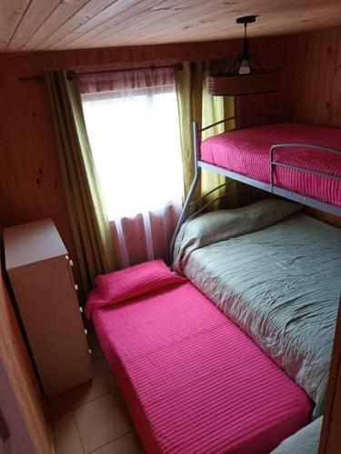a small room with two bunk beds and a window at Comoda Cabaña en Pichilemu in Pichilemu