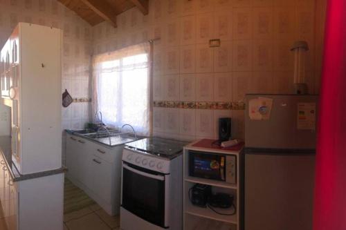 a kitchen with a refrigerator and a stove top oven at Comoda Cabaña en Pichilemu in Pichilemu