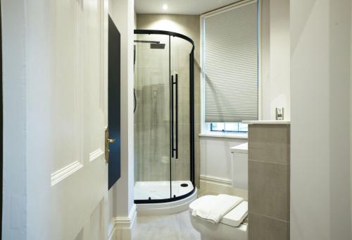 La salle de bains est pourvue de toilettes et d'une douche en verre. dans l'établissement Old Market Apartments, à Altrincham