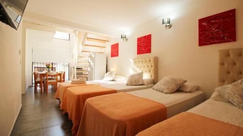a room with four beds with orange sheets and a table at Puerto Tigre in Tigre