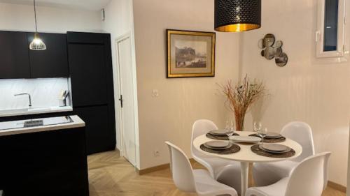 a kitchen with a white table and white chairs at Le Charmant in Tours