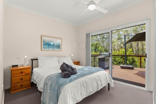 a bedroom with a bed and a sliding glass door at Rocks Place by Experience Jervis Bay in Vincentia
