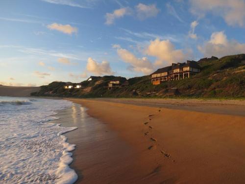 a beach with footprints in the sand and houses at Luxury Beach Villa - Mozambique in Inhambane