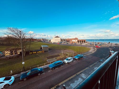 a group of cars parked on a road near the ocean at Spanish City View 2, Luxury Sea Front Apartment Free Onsite Parking in Whitley Bay