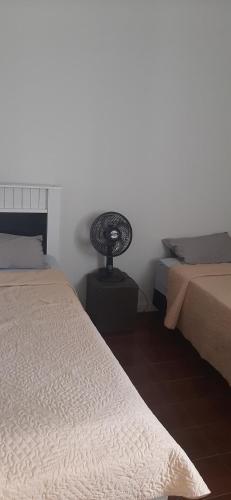 een slaapkamer met 2 bedden en een tafel met een ventilator bij Lugar Certo Tranquilo in Itabira