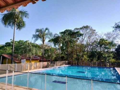 a large swimming pool with a fence and palm trees at Casa Tanure in Pirenópolis