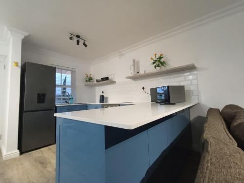 a kitchen with blue cabinets and a black refrigerator at Sunny Side Apartment in Knysna