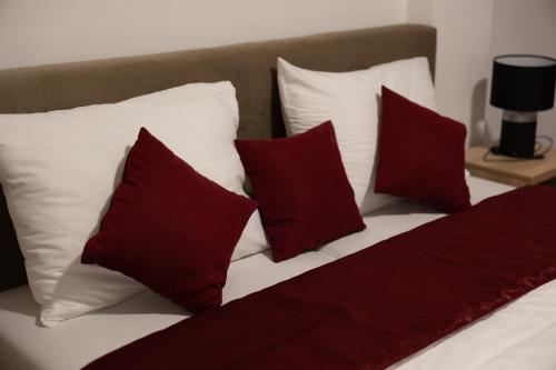 a group of pillows on a bed with red and white pillows at Hotel Muška voda in Kladanj