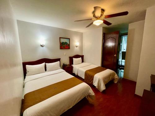 a hotel room with two beds and a ceiling fan at Hotel Puebla Plaza in Puebla
