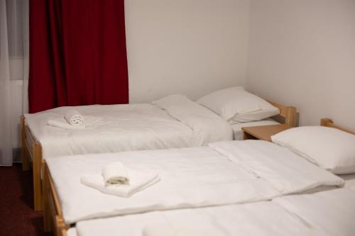 three beds in a room with white sheets and towels at Hotel Muška voda in Kladanj